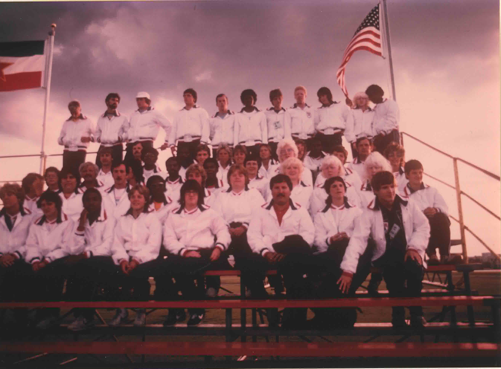 The USA Team sits in the bleachers wearing matching white jackets.