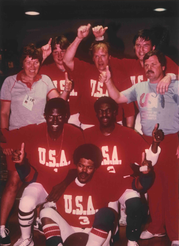 The USA men's team raises their arms in victory wearing red USA jerseys.