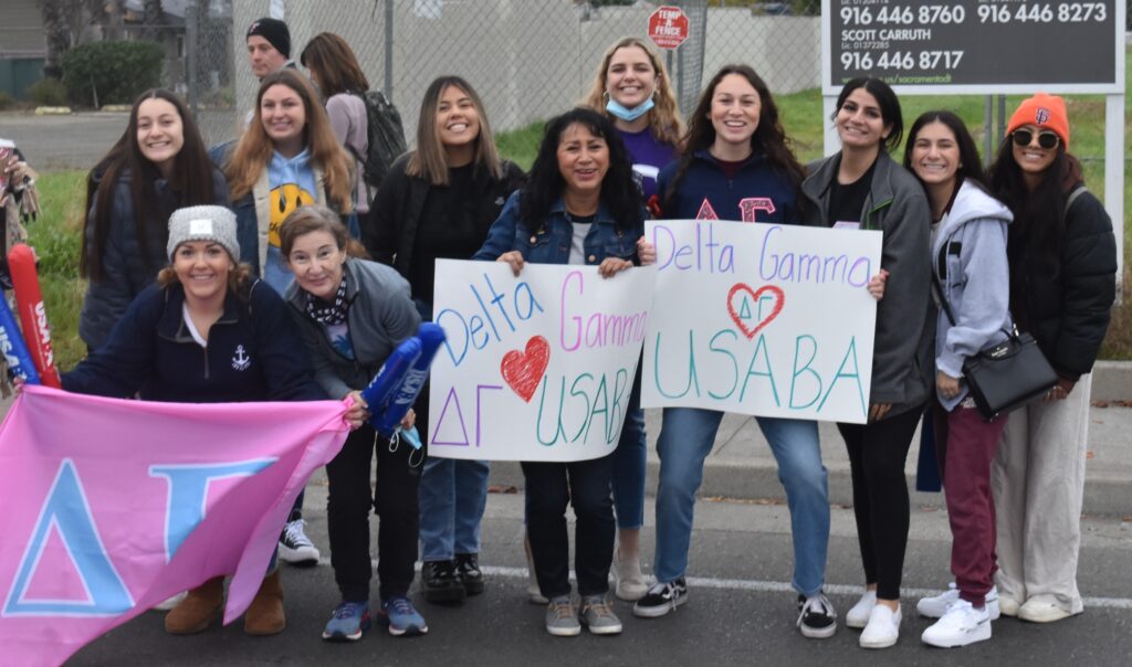 A group of Delta Gamma members display signs that read "Delta Gamma loves USABA" while they cheer on the runners at the California International Marathon.