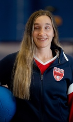 Eliana Mason poses with a goalball under her right arm while wearing a USA Goalball National Team jacket.