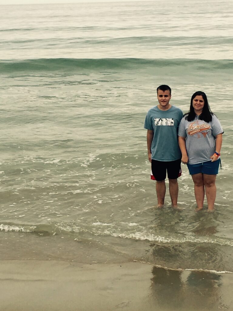 Wearing t-shirts and shorts, Libby and her younger brother Steven face the camera as they stand in the shallow surf off the coast of Maine.