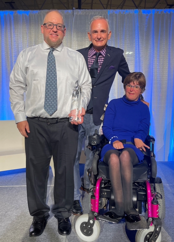 Jake Czechowski poses with Mark and Anne Plassman while holding the Ronald W. Plassman Gold Standard Award.