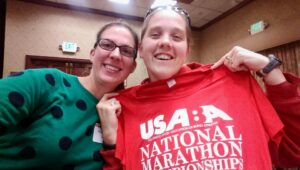 Jessica Heim wears a green polka dot shirt as she poses with a runner she guided for at the USABA Marathon National Championships