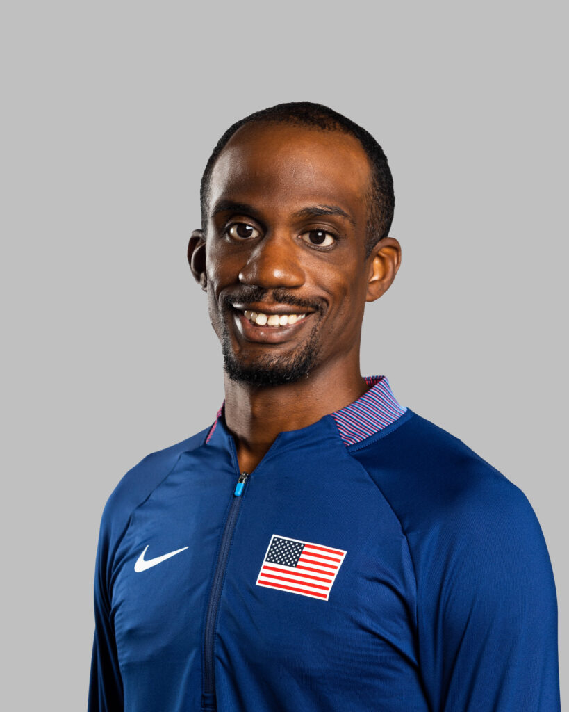 A headshot photo of Lex Gillette wearing a blue Nike jacket with an American flag on the chest