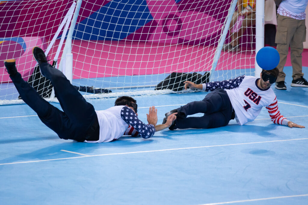 Matt Simpson (r) and teammate Tyler Merren slide and dive across the floor in front of their goal to combine on making a stop at the 2019 Parapan American Games in Lima, Peru.