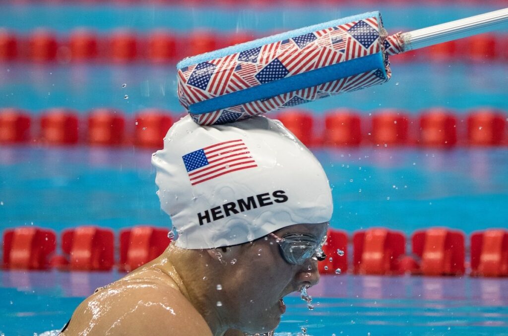 McClain Hermes is tapped on the head by a coach during a swimming race