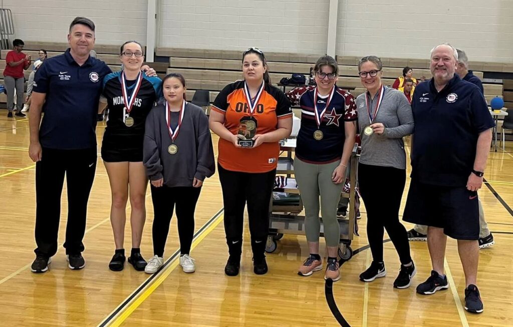 Members of the Ohio Monarchs women's team pose on the court with their trophy and medals.